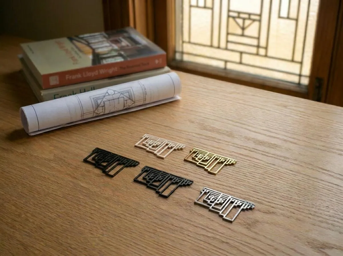 Five Graham's Necklace pendants in different finishes on a desk beside two books on Frank Lloyd Wright