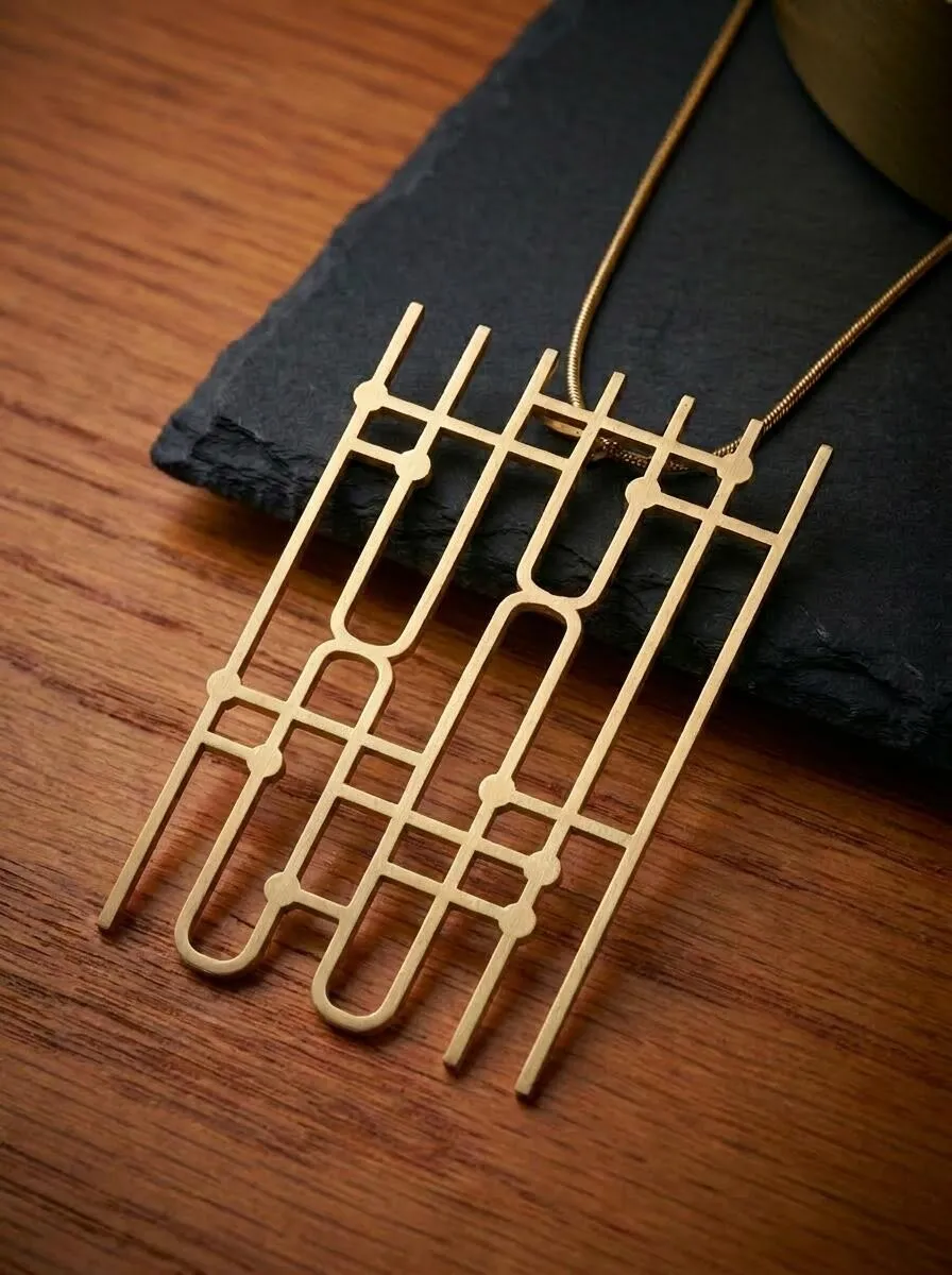 The Quantum Necklace in brass, lying on slate